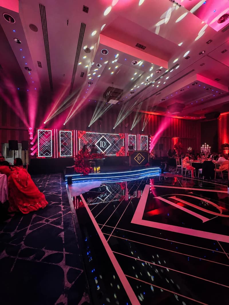 A red-lit wedding dancefloor and DJ booth ready for a mehndi night