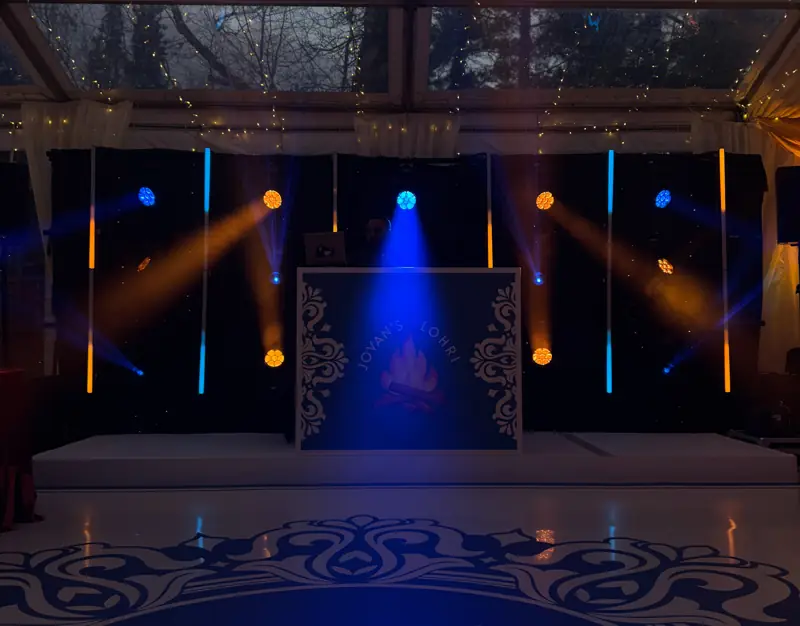 Booth and draping washed in blue and amber light around a printed dancefloor