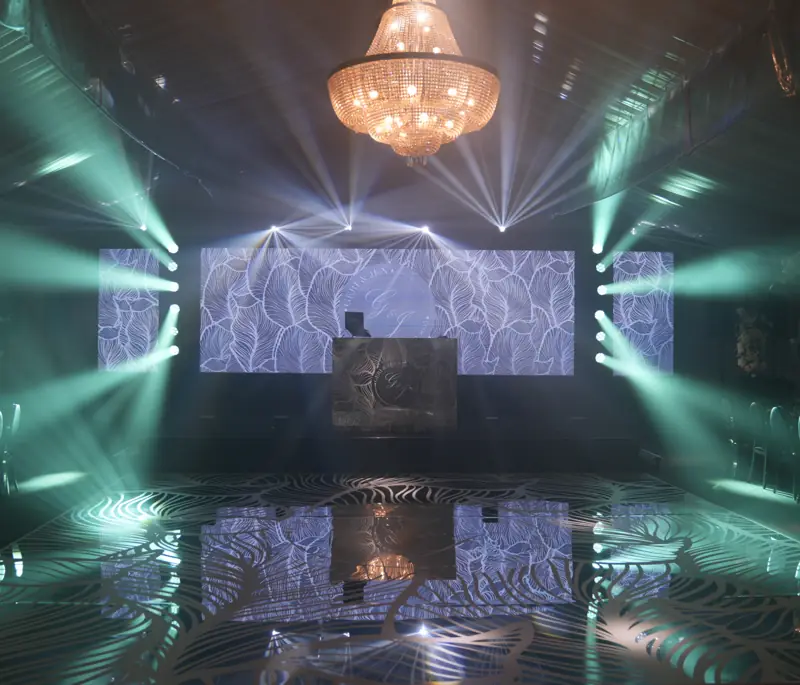 Ballroom with a chandelier, LED wall and white beams ready for the grand entrance