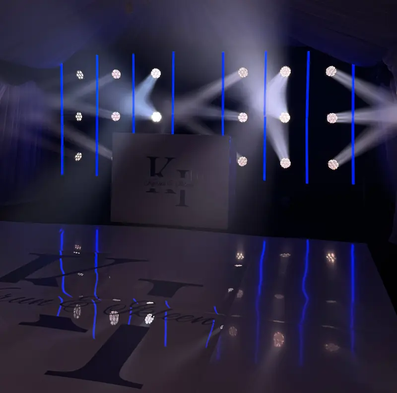 Moving-head beams crossing over a dance floor printed with the couple’s monogram