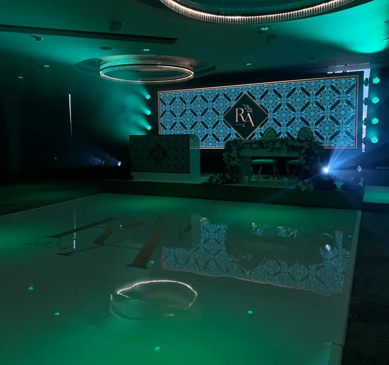 LED wall carrying a couple’s monogram behind the top table, room lit in green