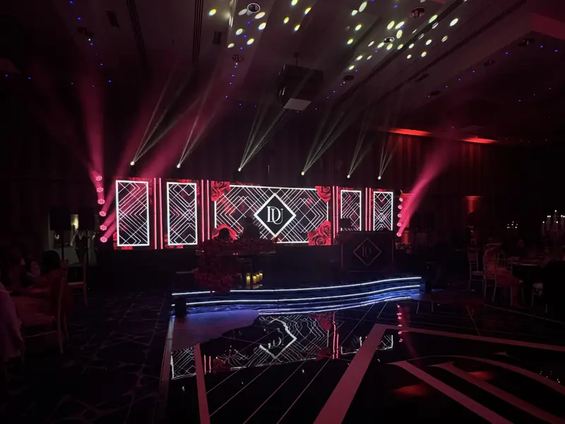Curved LED-edged riser under the DJ booth in front of a monogram stage