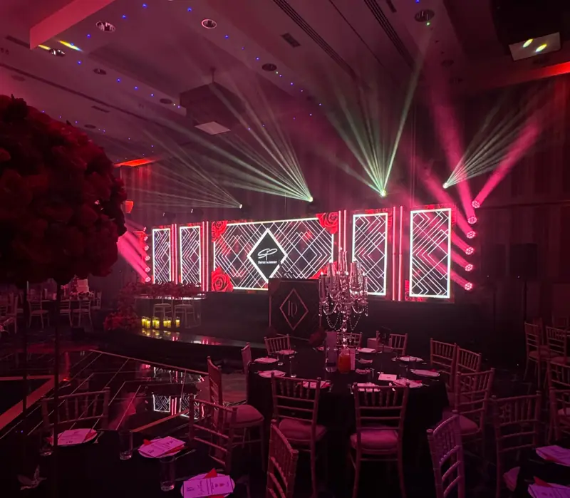 Monogram DJ booth front under red light and white beams