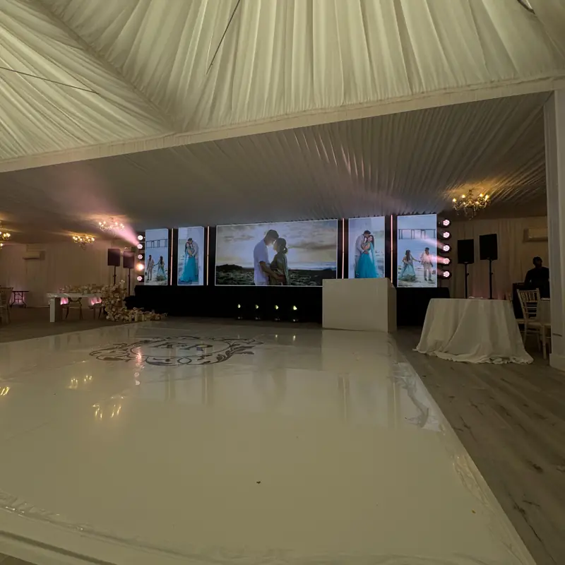 White dancefloor printed with a monogram in front of an LED wall in a marquee